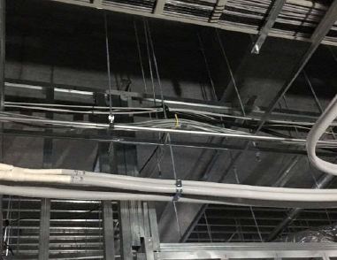 新築店舗の天井内に吊り金物で支持した電気配線の束と空調配管