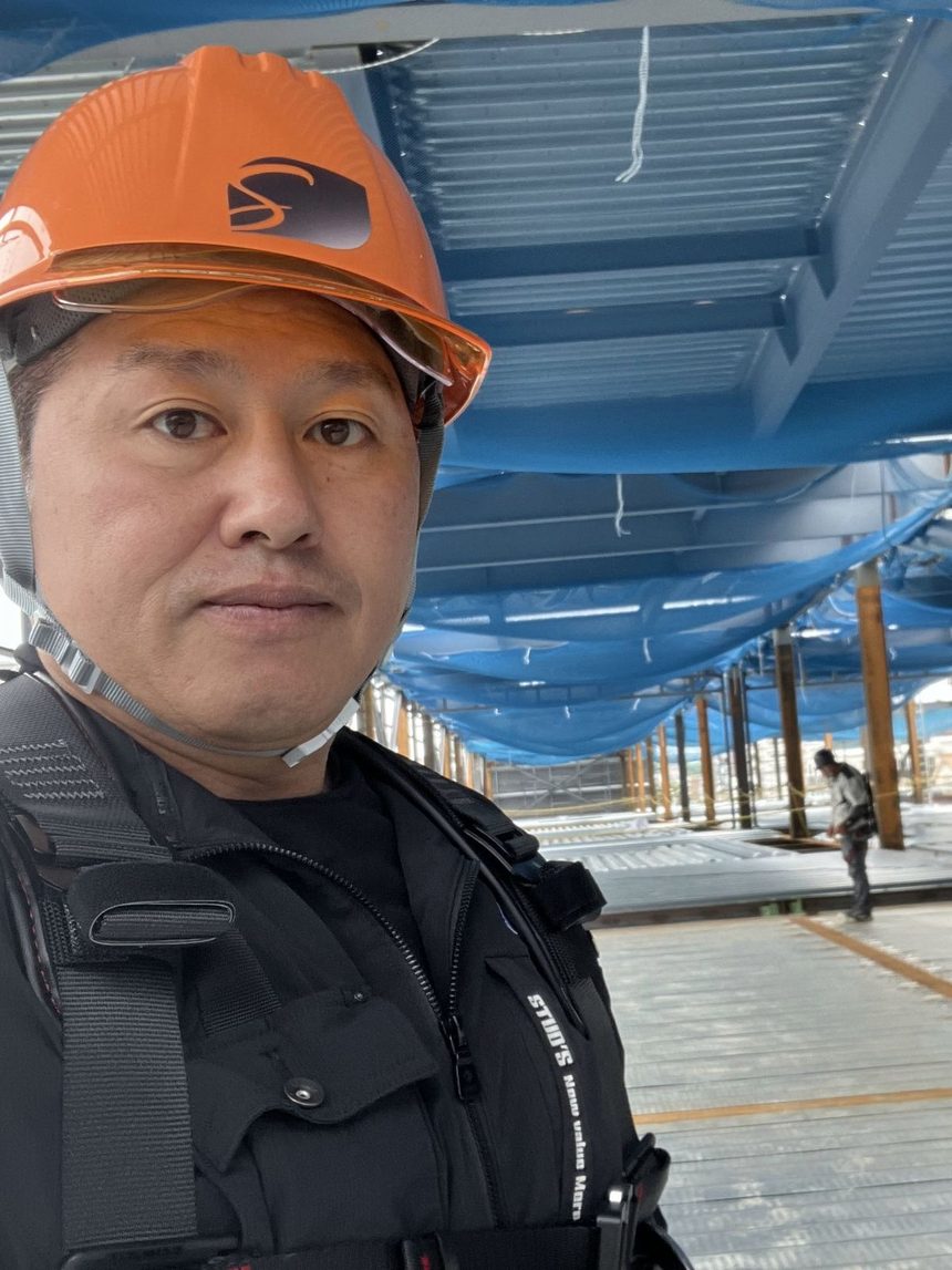 ヘルメットと安全帯を着けて現場に立つ代表取締役 和合崇志