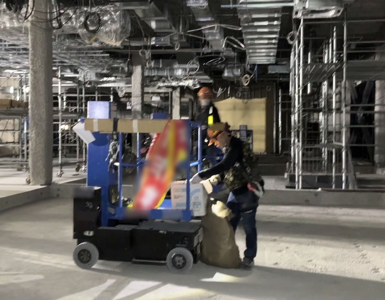 建設中のフロアで資材を高所作業車に積み込む職人